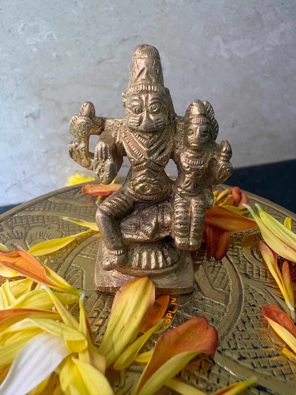Bronze statue of a deity on a decorative plate with flowers